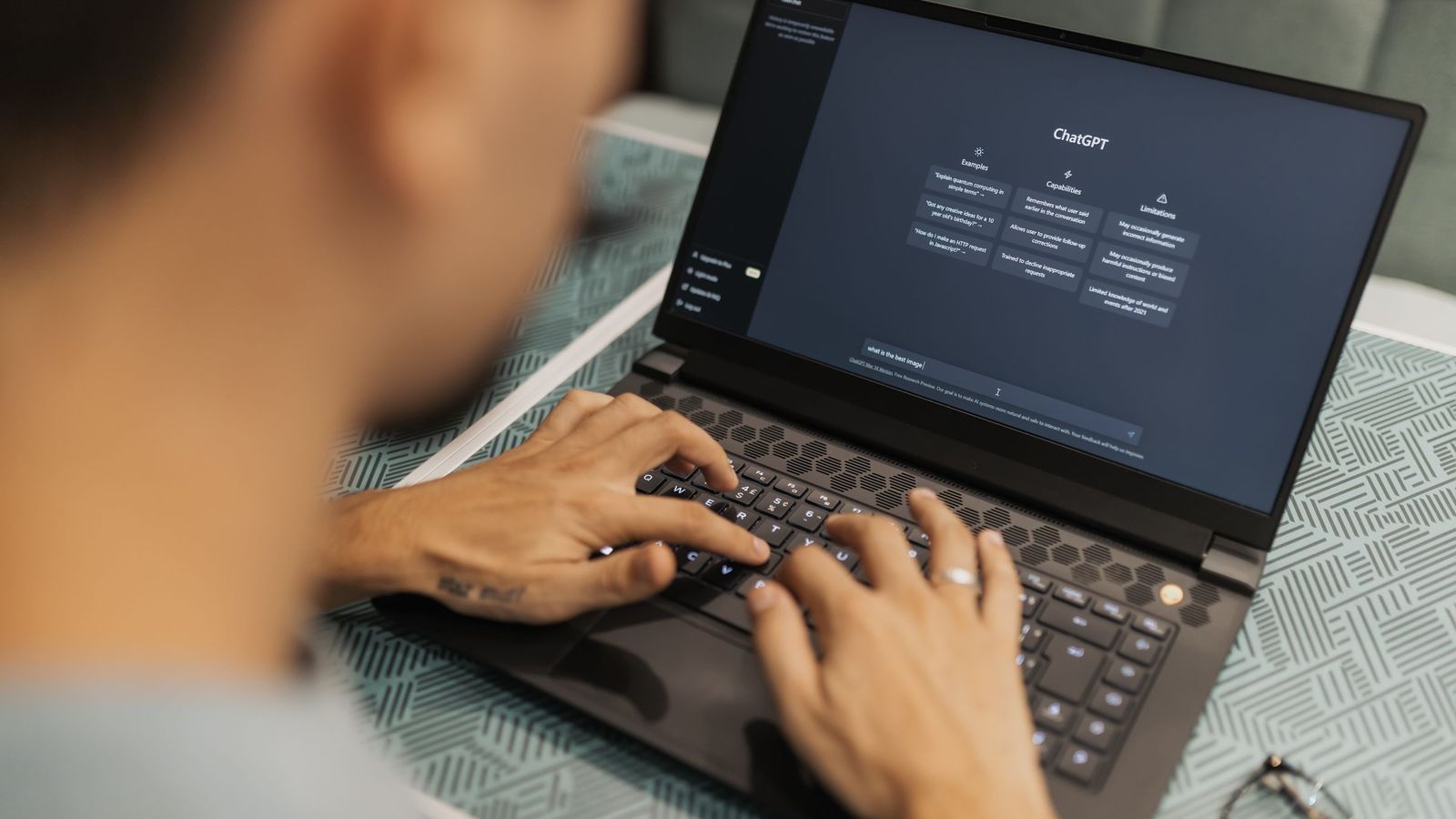 Une personne tape une demande dans un assistant d'intelligence artificielle sur un ordinateur portable.